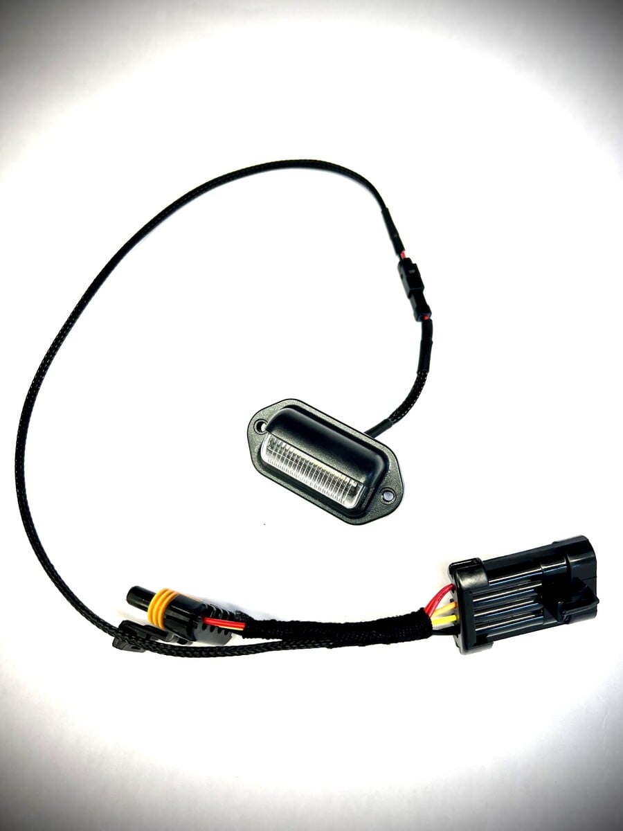 Black LED license plate light with wiring harness connector.
